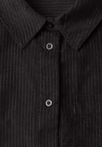 Chemise noire en velours côtelé avec col pointu et boutons argentés embossés du texte « "Street One" ».