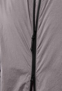 Leichte graue Jacke mit strukturiertem Finish, verfügt über einen schwarzen Reißverschluss und einen Ziehriemen, entworfen für eine schlanke Passform.