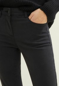 Juodos medvilnės mišinys kelnės su liesu siluetu, turinčios užtrauktuką ir mygtuko uždarymą, priekinėmis kišenėmis ir lygiu, tekstūruotu audiniu.