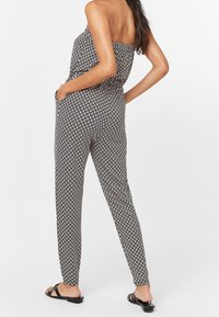 Combinaison sans manches à motifs noir et blanc avec un corsage ajusté, des jambes fuselées et des poches latérales. Matière légère au toucher doux.