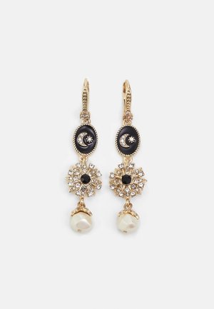 Oorbellen met goudkleurige afneembare hanger met zwarte geëmailleerde halve manen en sterren, met kristallen versierde zonnestralen en witte parelhangertjes op een witte achtergrond.