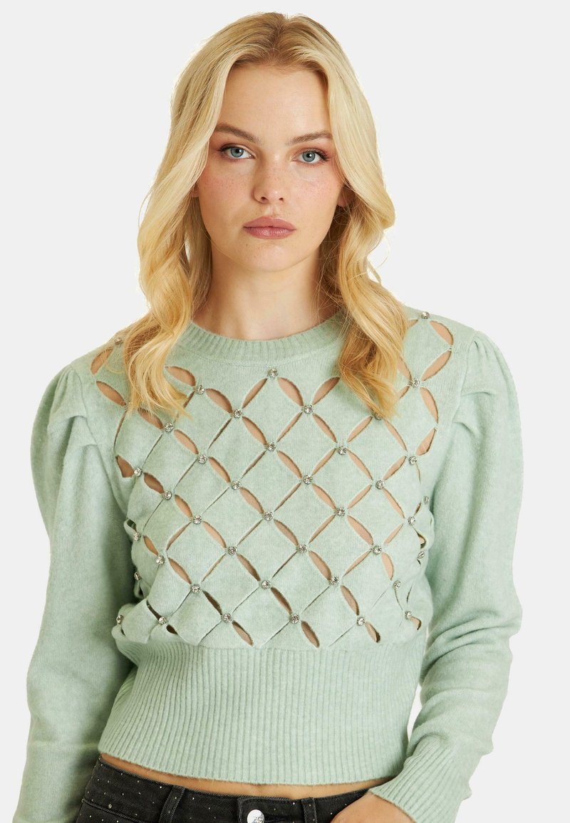 Maglione lavorato a maglia verde menta con maniche a sbuffo, caratterizzato da tagli a diamante e pietre decorative. Fondo a coste in vita.