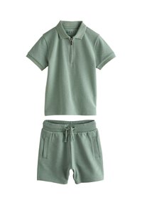 Two-piece outfit: short-sleeve polo with zip neck and matching shorts. Both are textured, light green, with side pockets on shorts.