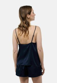 Ensemble de sommeil en satin bleu marine avec un ourlet à volants. Comprend des bretelles spaghetti ajustables et un haut ample assorti à un short.