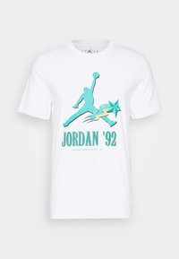 Camiseta de algodón blanca con un gráfico turquesa de un jugador de baloncesto en movimiento, con el texto "JORDAN '92" abajo.