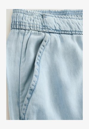 Ljusblå denimshorts med elastisk midjeband, sidfickor och mjuk textur; har distinkt sömnad längs sömmarna.