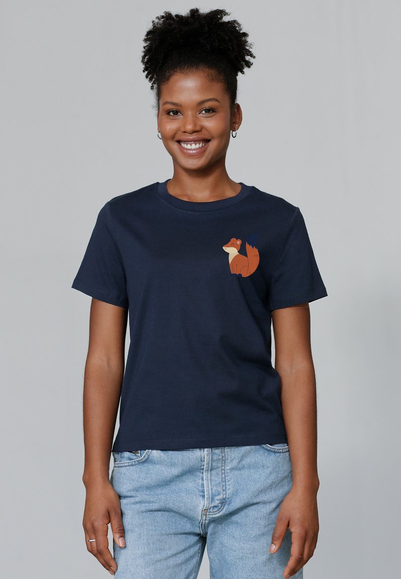 T-shirt en coton bleu marine avec un petit graphique de renard orange sur le côté gauche de la poitrine. Manches courtes et design classique à col rond.