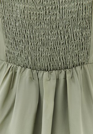 Groene jurk met een smockbustier en getextureerde plooien, gemaakt van lichtgewicht stof, wat zorgt voor een vloeiende silhouet.