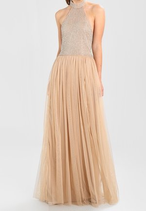Beige halter-neck jurk met een zwaar versierde, met kralen bezette corsage en een vloeiende, geplooide tule rok, waardoor er een zachte, gelaagde textuur ontstaat.