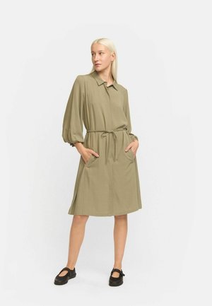 Olivgrünes Kleid mit Kragen, puffärmeligen Ärmeln, einer Kordelzugtaille und zwei Seitenöffnungen. Glatte Textur, knielanges Design.