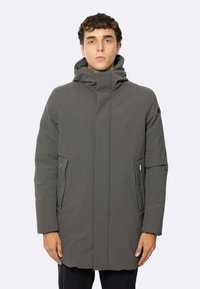 Cappotto grigio impermeabile con colletto alto, chiusura frontale nascosta e tasche laterali. Presenta un tessuto liscio e testurizzato e una vestibilità comoda.