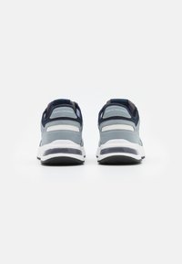 Sneakers cinza-azuis com um upper em camurça texturizada e malha, entressola branca e detalhes em azul-marinho. Apresenta logótipo no calcanhar e uma sola acolchoada.