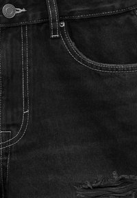 Zwarte denimshorts met een versleten zoom, contrasterende witte stiksels en een metalen knoopsluiting. Detail van de zak zichtbaar.