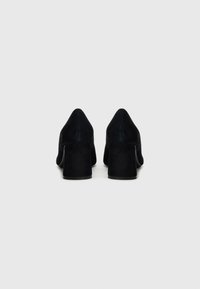 Sorte semskede høyhælte sko med spiss tå og bred blokkhel, med en glatt tekstur og et rent, minimalistisk design.