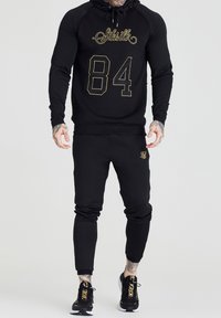 Set di felpa con cappuccio e pantaloni jogger realizzato in misto cotone, con stampa dorata delle scritte "Siksilk" e "84". Include un cappuccio regolabile e pantaloni affusolati.