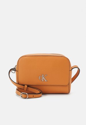 Kompakt tanfarvet læder crossbody taske med justerbar strop, sølv Calvin Klein "cK" logo på frontklappen og lynlåslukning på toppen.