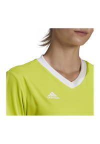 Felgroen sportshirt met een witte V-hals en korte mouwen. Bevat een wit Adidas-logo aan de linkerkant van de borst.