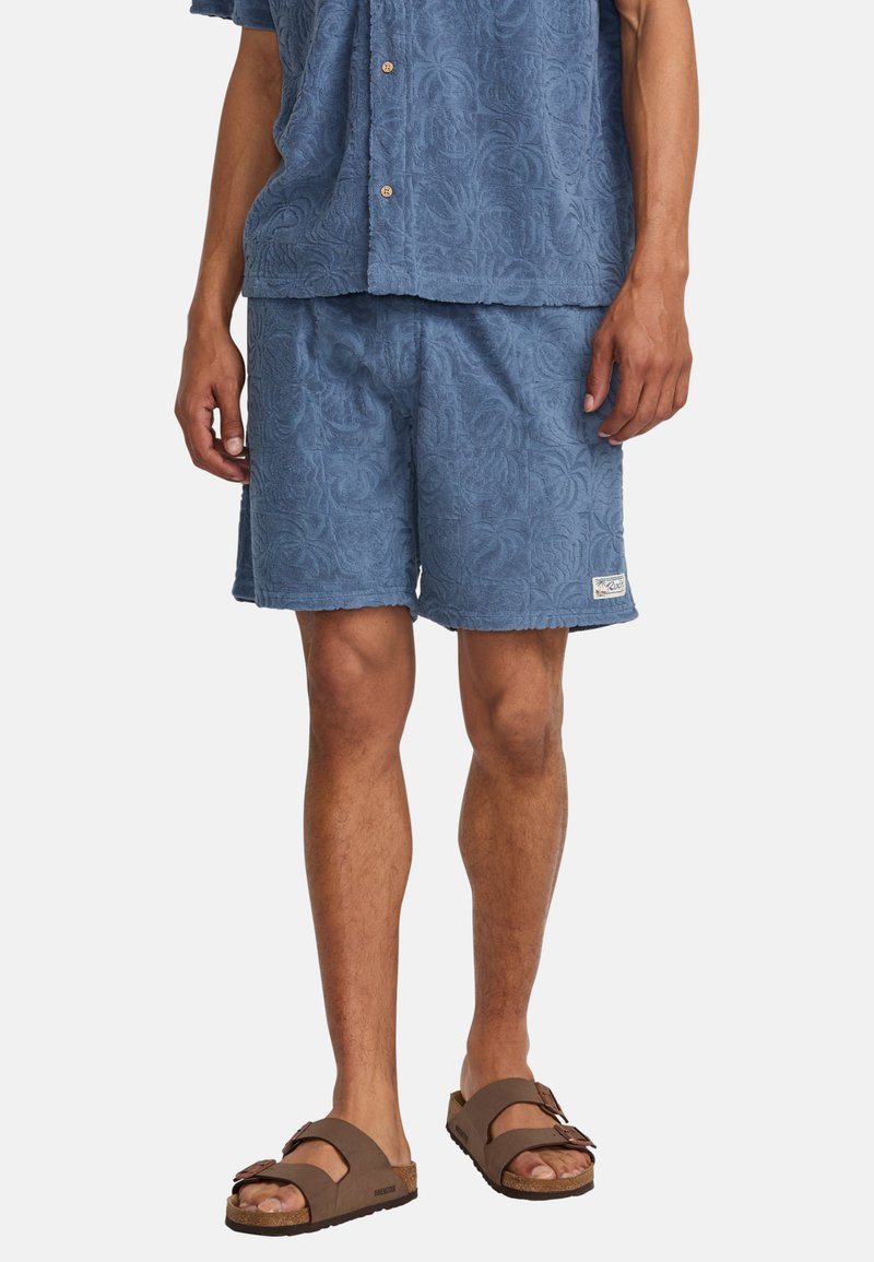 Blue textured shorts with a floral pattern, made of soft fabric. Paired with a matching short-sleeve shirt and brown sandals.