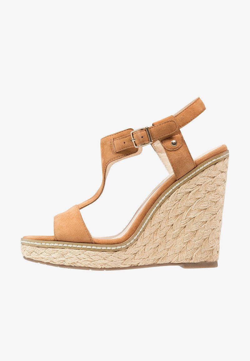 Sandale en suède marron à talon compensé avec une semelle en jute tressé, bout ouvert et bride de cheville réglable avec une boucle métallique.