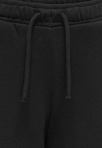 Mustat collegehousut pehmeällä tekstuurilla, joissa on joustava vyötärö, nyörisuljenta ja sileä kangaspinta.