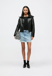 Μαύρο cropped δερμάτινο μπουφάν με oversized γιακά, συνδυασμένο με ανοιχτό μπλε τζιν mini φούστα και τσάντα με υφή από φίδι. Μαύρες ankle boots.