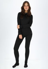 Sort termoundssæt bestående af en langærmet top og tætsiddende leggins. Stoffet har en ribbet tekstur med en diskret logo-detalje ved kanten.