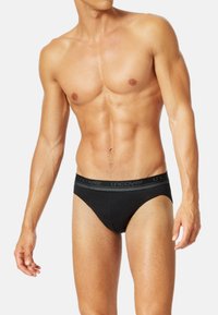 Caleçons noirs en coton avec une ceinture élastique confortable portant le texte "dévoiler" en gris. Design ajusté avec une couverture minimale.