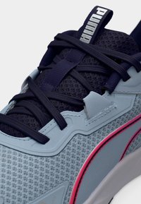 Αθλητικό παπούτσι ανοιχτού μπλε χρώματος με επάνω μέρος από δίχτυ, σκούρες μπλε κορδόνια και ροζ λεπτομέρειες. Διαθέτει υφή στην επιφάνεια και καουτσούκ σόλα για καλύτερη πρόσφυση.