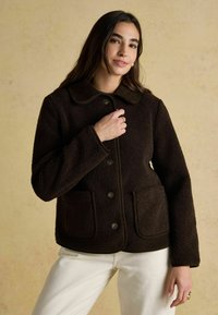 Hnedá fleecová bunda s okrúhlym golierom, dvoma prednými vreckami a zapínaním na gombíky. Textúrovaná tkanina s kontrastnými detailmi.