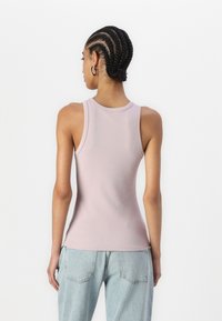 Lys rosa ribbet tanktop med en tettsittende design, med rund hals og uten ermer, kombinert med lyse blå jeans.