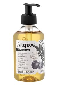 Bottiglia rotonda trasparente con un tappo a pompa nero. Contiene un fluido detergente giallo. Presenta un'etichetta bianca con testo nero e illustrazioni botaniche.