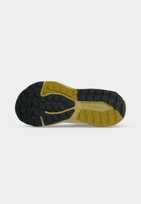Semelle de chaussure de sport New Balance avec un motif de bande de roulement texturé noir et jaune et le texte "new balance" au centre.