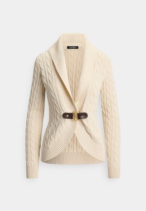 Kremhvit kabelstrikket cardigan med sjalkrage og brun skinnspenne. Har ribbestrikkede mansjetter og kant for teksturert finish.
