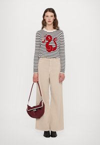 Striped sweater with a red snake design, beige wide-leg pants, and a burgundy handbag. Shoes are black, with silver hardware on the bag.