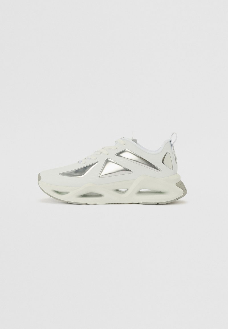 Hvit sneakers med metalliske detaljer, mesh-detaljering og en kraftig såle. Har en buet form og snøring for sikker passform.
