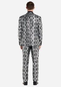 Schwarz-weißer Schlangenprint-Anzug mit glänzendem Finish, bestehend aus einem einreihigen Blazer und geraden Hosen.