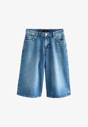 Heledad sinineid teksaseelikuid, millel on lahtine lõige, standardne viie taskuga disain ja nööpidega vöökoht.