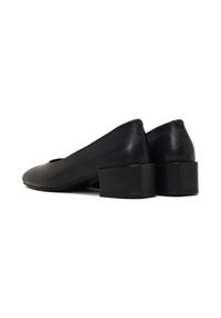 Chaussures slip-on en cuir noir avec un bout arrondi et un petit talon carré. Texture lisse et design minimaliste sans embellissements.