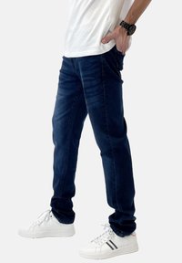 Jeans azul marino de corte slim, con una textura suave y un ligero desvanecimiento. Combinados con zapatillas blancas y una camiseta blanca básica.