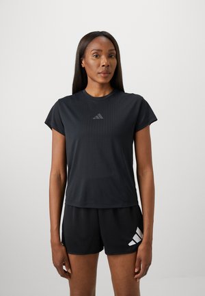 T-shirt de sport noir à manches courtes, avec une texture rayée subtile et un logo réfléchissant sur le devant. Assorti à des shorts noirs.