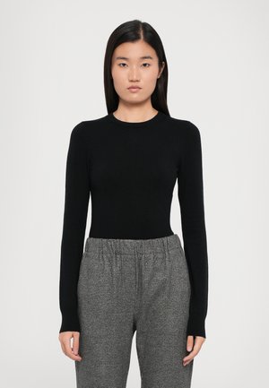 Black long-sleeve fitted top with a round neckline, paired with gray patterned trousers featuring an elastic waistband and loose fit.