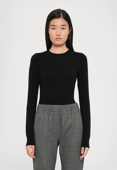 Black long-sleeve fitted top with a round neckline, paired with gray patterned trousers featuring an elastic waistband and loose fit.