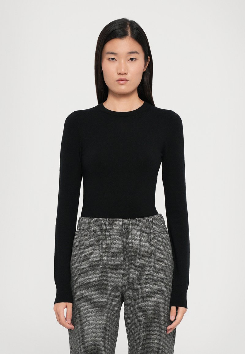 Black long-sleeve fitted top with a round neckline, paired with gray patterned trousers featuring an elastic waistband and loose fit.