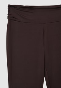 Pantaloni in tessuto elasticizzato di colore marrone scuro con una ampia vita elastica arricciata nella parte superiore.