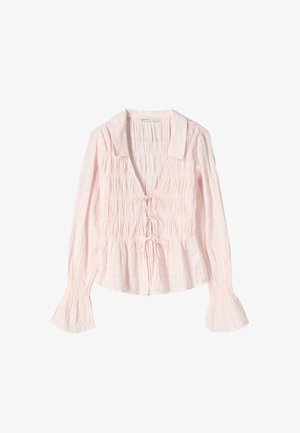 Svetloružová blúzka s golierom, smockovaným telom a viazaním vpredu. Má dlhé rukávy s rozšírenými manžetami a textúrovanú látku.