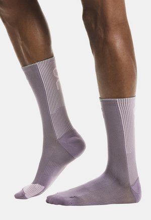 Lila sportzokni texturált mintával, bordázott részletekkel, megerősített orr-résszel és a felső résznél elhelyezett logóval.