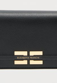 Μαύρο πορτοφόλι από δερματίνη με υφή, διακοσμημένο με χρυσό λογότυπο και λεπτομέρειες. Ο σχεδιασμός έχει ορθογώνιο σχήμα με λεία επιφάνεια.