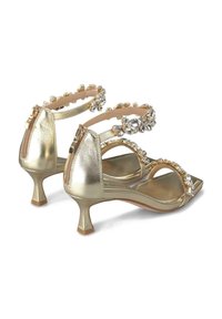 Sandales à talons métalliques dorées avec un bout carré, une bride ornée de strass transparents et une fermeture zippée à l'arrière.