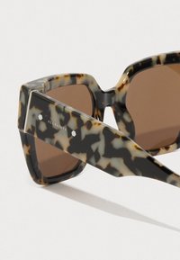 Skilpaddeskall solbriller med overdimensjonerte firkantede rammer, brune linser og sølvdetaljer på brillestengene. Logo gravert på siden.