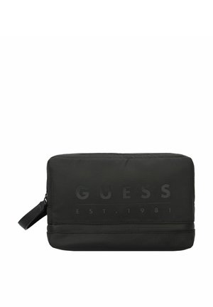 Zwarte nylon toilettas met een gladde textuur, reliëf "GUESS" logo, ritssluiting en een handvat aan de zijkant voor gemakkelijk transport.
